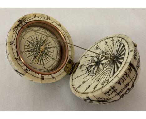 A carved bone scrimshaw style globe with hinged lid and compass inset to interior.   Approx. 7cm diameter.