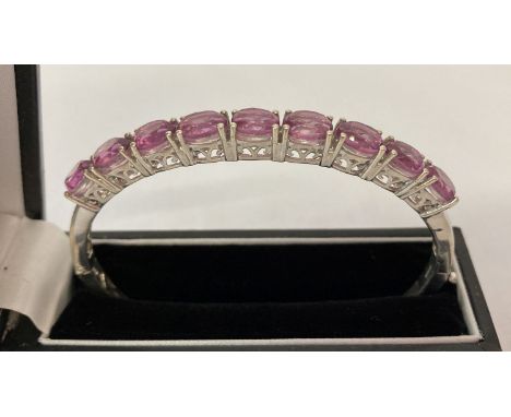 A silver hinged bangle set with 9 oval cut pink fluorite stones by TJC.  With original tags. Makers and 925 mark to inside of