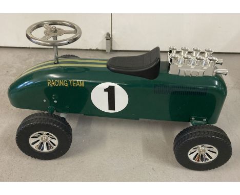 A vintage style children's ride on metal racing car, painted green.  With "Racing Team", No. 1 and yellow stripe decals. Chro
