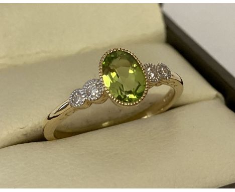 A 9ct gold peridot and diamond dress ring by Luke Stockley, London.  Oval cut central peridot with 2 small illusion set diamo