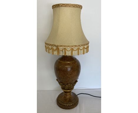 A gold coloured table lamp with leaf decoration and cream shade.   Approx. 75cm tall with shade.