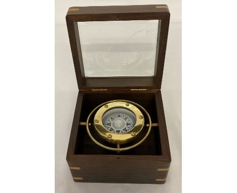 A modern small brass ships compass in a glass topped wooden box.   Box approx. 8cm tall x 12cm square.