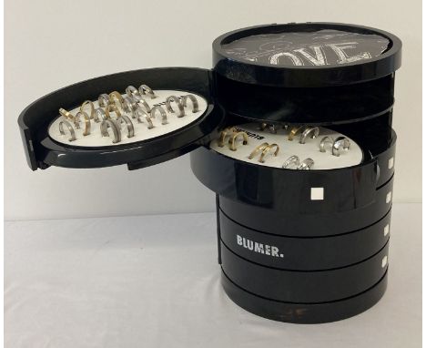 A "Blumer" black plastic ring stacking storage display unit containing 50+ silver &amp; gold tone rings.  Rings in varying st