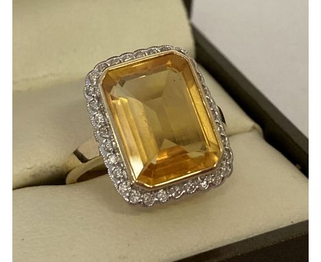 A 9ct gold citrine and diamond dress ring by Luke Stockley, London.  Large square cut citrine surrounded by small round cut d