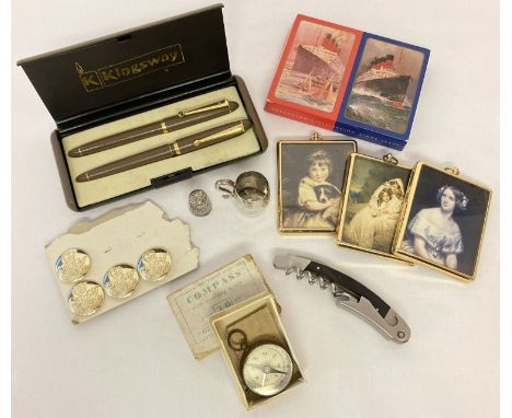 A collection of assorted misc. items to include boxed vest pocket compass, pen set, playing cards,  silver plated barrel tank