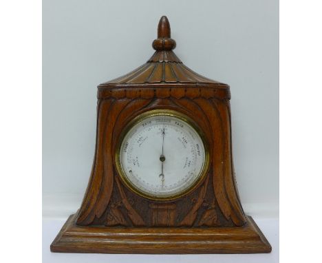 An aneroid barometer with thermometer in a carved oak case, tent, rifles and spiked helmets, height 31cm