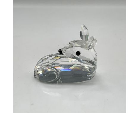 Clear crystal figure lies on its stomach with its head turned to the side, adorned with black crystal eyes. Swarovski backsta