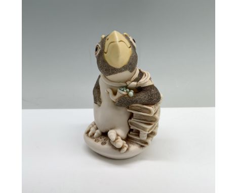 A box featuring a penguin with large yellow eyebrows and a matching beak, resting beside a stack of books while holding a bub