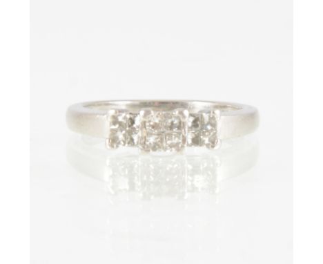 A Princess cut diamond ring, the twelve diamonds arranged in groups of four giving the impression of a three stone ring in an