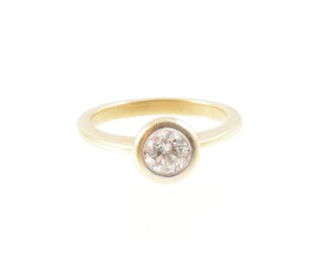 A diamond solitaire ring, the brilliant cut stone set in a round collet on an 18 carat yellow gold 2.1mm wide band with solid