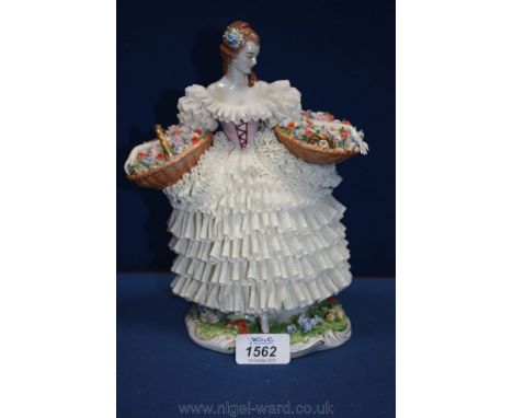 A Dresden figurine of a young lady carrying two baskets of flowers, 9 1/2'' tall