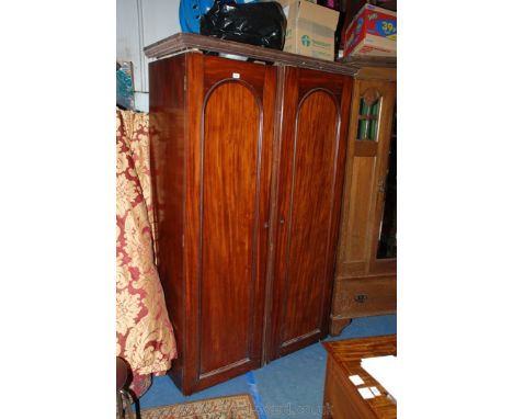 A Victorian Mahogany twin door Wardrobe having moulded cornice over the opposing pair of single moulded arch top panel doors 