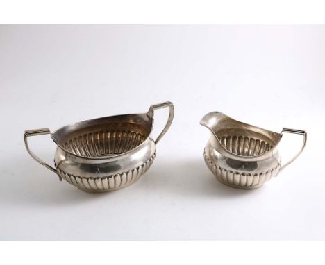 A GEORGE III IRISH CREAM JUG &amp; MATCHING SUGAR BASIN with part-fluted decoration and reeded angular handles, each piece in