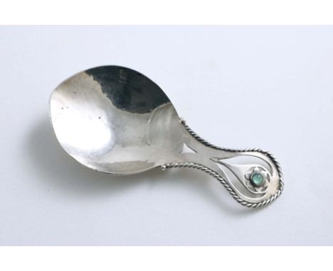 AN EARLY 20TH CENTURY ARTS &amp; CRAFTS CADDY SPOON with a hammered finish, a small green hardstone, floral boss, within a co