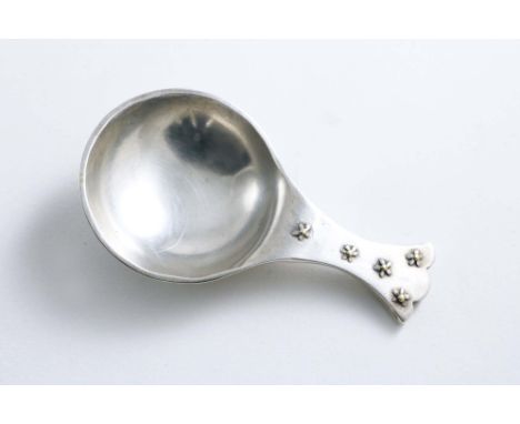 A CONTEMPORARY CADDY SPOON with a circular bowl and a trefoil terminal, decorated front &amp; back with applied daisy flowers