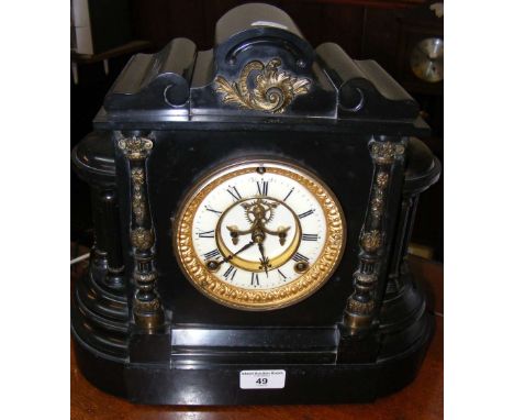 A slate cased striking mantel clock with visible escapement and brass embellishments to the side columns