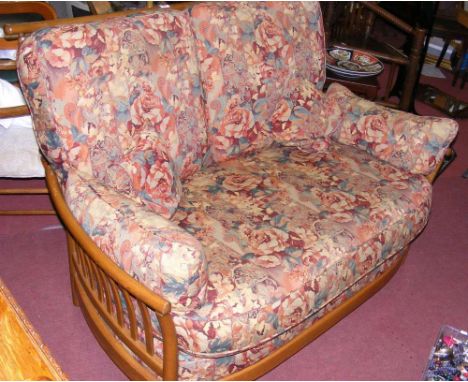 An Ercol elm two seater sofa with floral cushions