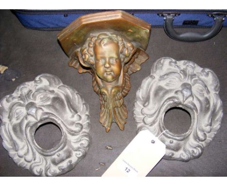 A pair of old lead lined masks embellishments and a plaster cherub wall bracket