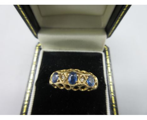18ct yellow gold ring set with three sapphires separated by diamonds in rub over setting, stamped 18, 3.3g