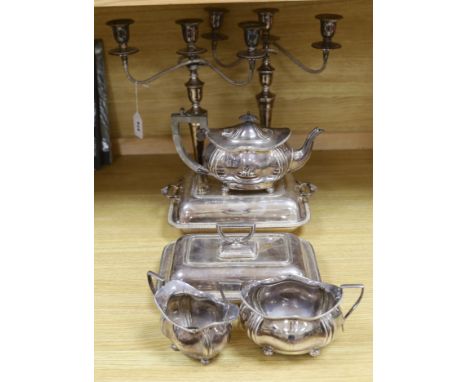 A group of silver plated items including a pair of three branched candlesticks, teapot, milk jug and sugar bowl, the largest 