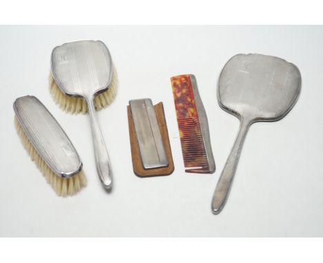 A George V silver backed four piece dressing table set, Birmingham, 1934 and one other silver cased comb.