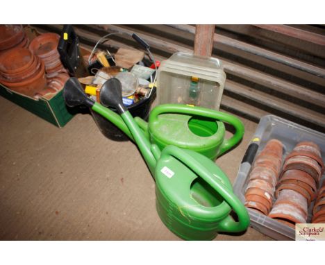 Two plastic watering cans; plant tray tops and a bucket of hand tools