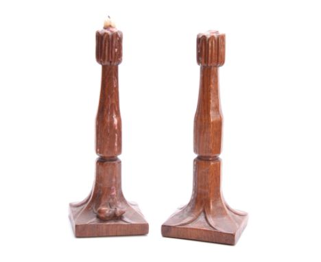 A PAIR OF EARLY ROBERT MOUSEMAN THOMPSON OAK CANDLESTICKS with leaf carved sconces and facetted ringed tapering stems on squa
