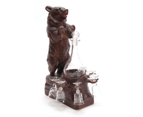 AN EARLY 20th CENTURY CARVED BLACK FOREST MUSICAL DECANTER STAND modelled as a standing bear beside a glass decanter held in 