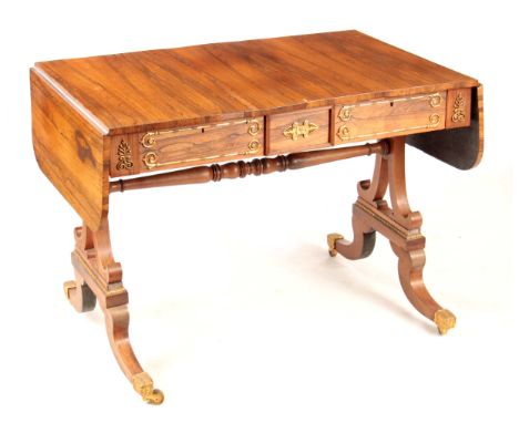 A REGENCY ROSEWOOD SOFA TABLE with gilded brass mounts, the top with fall down leaves and frieze drawers; standing on scrolle