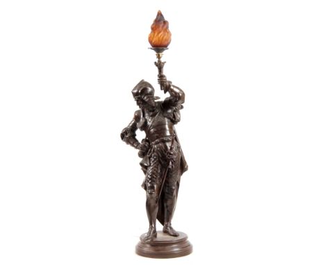 AN EARLY 20th CENTURY PATINATED BRONZED METAL FIGURAL LAMP modelled as a knight holding a torch with amber glass shade on cir
