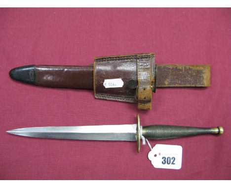 A Mid XX Century Fairburn-Sykes Fighting Knife, with brass hilt and cross guard; a mid XX century leather scabbard with metal