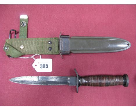 A Mid XX Century U.S. Fighting Knife, with leather grips, blade marked U.S. M3, cross guard loose, in its green plastic scabb