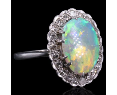 A very fine opal and diamond cluster ring comprising a central opal cabochon of approx 12 x 8.5 mm claw-set above an oval of 