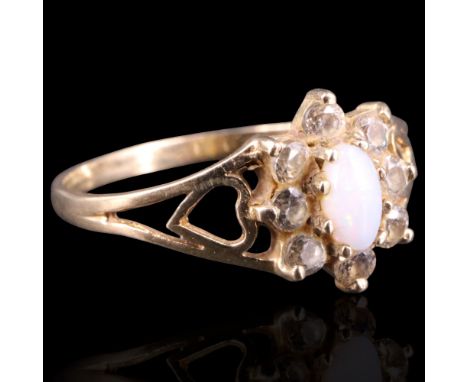 A 1990 opal and diamond flowerhead cluster ring, comprising an oval opal cabochon framed by small white stone brilliants claw