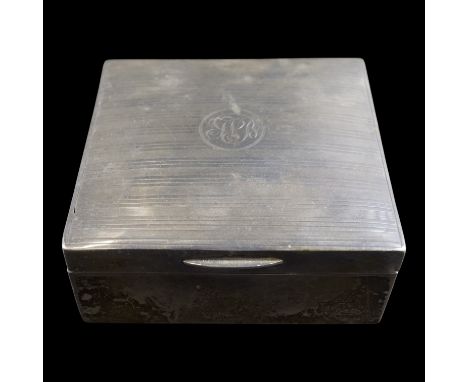 A George V silver cigarette box, its subtly domed hinged lid bearing linear engine-turned decoration centred by a cartouche a