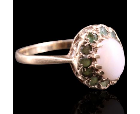 A 1977 opal and emerald ring comprising an oval opal cabochon of approx 7 mm x 5 mm framed by small round-cut emeralds above 