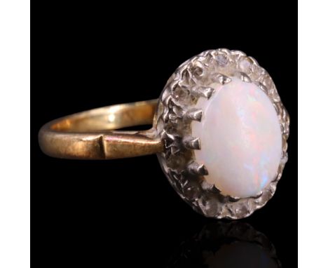 An opal and diamond dress ring comprising an oval cabochon of approx 9 x 7 mm claw-set within a border of illusion-set diamon