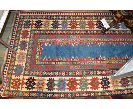 An antique Kazak long rug, having narrow plain central blue panel, within a framework of borders in red and cream with styliz