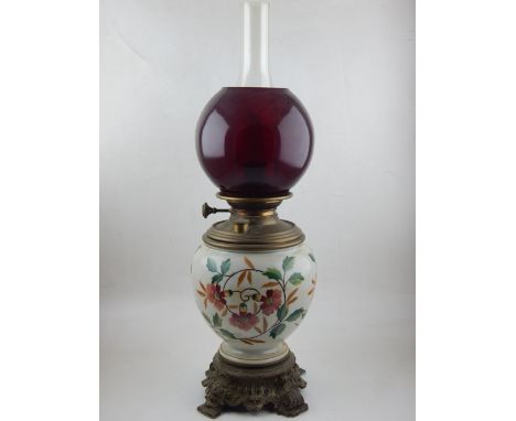 A late Victorian lamp, with a ceramic reservoir incorporating floral decoration and brass mounts, with a red glass shade, H. 