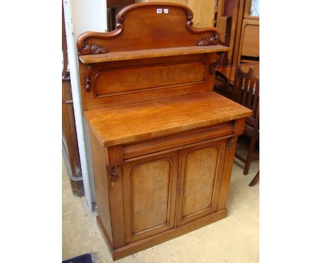 A mid 19th Century chiffonier, the single shelf raised on scrolled supports over a single long cushion drawer over a cupboard