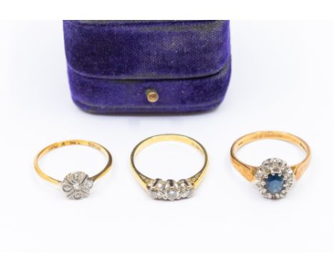 Three stone set 18ct gold rings, to include an Edwardian diamond set flower cluster ring, size M,  cased, along with a three 