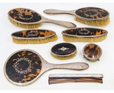 A matching George V silver and faux tortoiseshell dressing table set consisting of hand mirror, two hand mirrors, and two ova