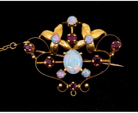 An Edwardian opal and ruby set 18ct gold brooch, comprising an open wire work form with gold floral decoration, set to the ce