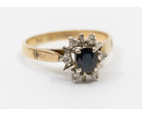 A sapphire and diamond 9ct gold ring, comprising an oval claw set sapphire set to the centre with a border of diamonds and al