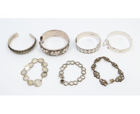 A collection of silver and white metal bangles and bracelets, to include a silver hinged bangle with embossed grape vine deco