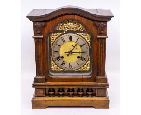 A late 19th/early 20th century wooden bracket clock, gilt metal dial and column supports and with arched top.