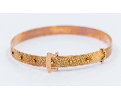 An early 20th century 9ct rose gold bangle in the form of a buckle, comprising machine engraved decoration, with adjustable b