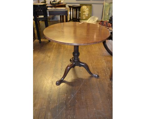 A George III mahogany tea table, the circular top raised on a baluster ring turned column support, tripod base with slipper f