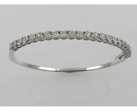 A white metal and diamond bangle bracelet, set 23 stones of approx. 0.5 carats combined. 