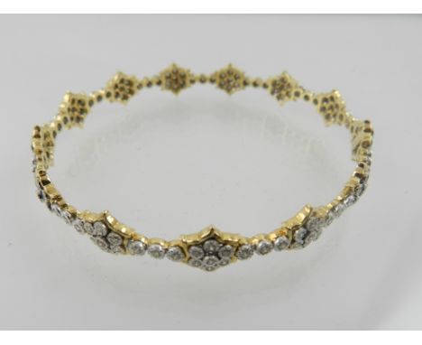 An 18 carat yellow gold and diamond bangle, set with multiple flowerhead clusters divided by three stone bands, the stones of